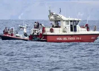 Buzos de los bomberos italianos llevan hasta un barco la bolsa con los restos mortales de una de las víctimas del naufragio del yate Bayesian, el 21 de agosto de 2024, en Porticello, cerca de Palermo, en el sur de Italia. (AP Foto/Salvatore Cavalli)