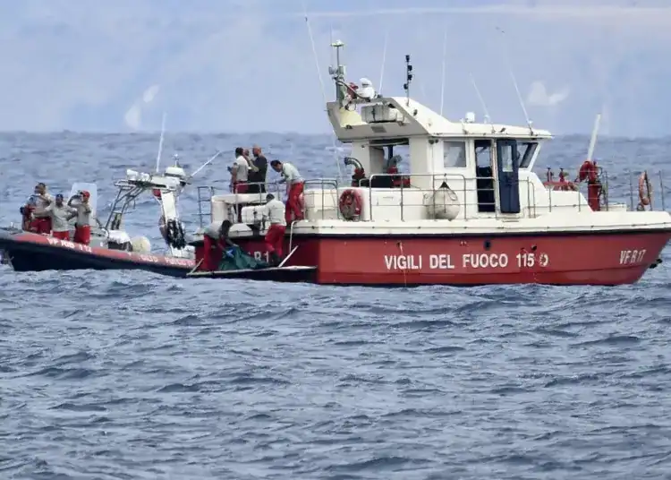 Buzos de los bomberos italianos llevan hasta un barco la bolsa con los restos mortales de una de las víctimas del naufragio del yate Bayesian, el 21 de agosto de 2024, en Porticello, cerca de Palermo, en el sur de Italia. (AP Foto/Salvatore Cavalli)
