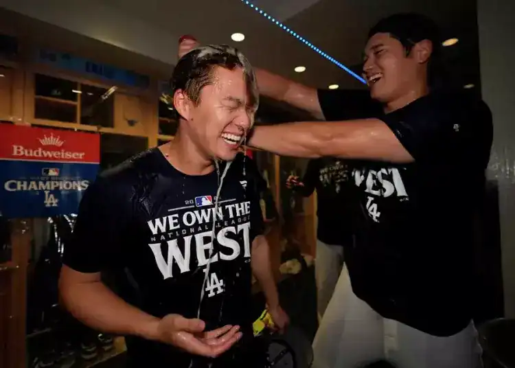 El japonés Shohei Ohtani, bateador designado de los Dodgers de Los Ángeles, arroja champaña encima de su compatriota Yoshinobu Yamamoto, luego de la conquista del cetro de la División Oeste de la Liga Nacional con un triunfo sobre los Padres de San Diego, el jueves 26 de septiembre de 2024 (AP Foto/Ashley Landis)