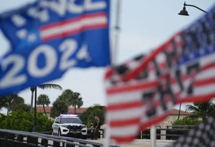 Policías resguardan un puente ubicado a un costado de la finca Mar-a-Lago del expresidente Donald Trump mientras un simpatizante ondea banderas para expresar su apoyo a Trump, un día después de un aparente intento de asesinato en su contra, el lunes 16 de septiembre de 2024, en Palm Beach, Florida. ((Rebecca Blackwell/AP))