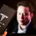 In this photo illustration the Tesla logo, US leading EV cars producer, is shown on a mobile phone screen against the Elon Musk portrait displayed on a computer screen as Tesla sales drop in worldwide as Elon Musk, the owner of Tesla, backs far right politicians -February 9, 2025. (Photo by Dominika Zarzycka/NurPhoto via Getty Images)
