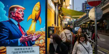 People walk past a cartoon image of US President Donald Trump with Bitcoin tokens at a Coinhero store in Hong Kong, China, on Friday, March 7, 2025. A simmering tension in the crypto industry resurfaced after President Donald Trump signed a long-awaited order creating a strategic Bitcoin reserve and an additional stockpile of other digital assets. Photographer: Leung Man Hei/Bloomberg via Getty Images