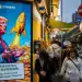 People walk past a cartoon image of US President Donald Trump with Bitcoin tokens at a Coinhero store in Hong Kong, China, on Friday, March 7, 2025. A simmering tension in the crypto industry resurfaced after President Donald Trump signed a long-awaited order creating a strategic Bitcoin reserve and an additional stockpile of other digital assets. Photographer: Leung Man Hei/Bloomberg via Getty Images