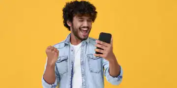 Joven emocionado y feliz ganador de un joven indio, sintiendo alegría al usar el juego de lotería ganadora de un smartphone