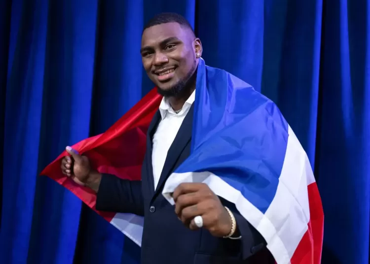 Bayron Matos sosteniendo una bandera de República Dominicana en la espalda