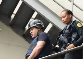 Oficial de la Policía Nacional escolta a Mantequilla con casco y chaleco antibalas por una escalera metálica en un operativo de seguridad.