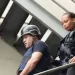 Oficial de la Policía Nacional escolta a Mantequilla con casco y chaleco antibalas por una escalera metálica en un operativo de seguridad.