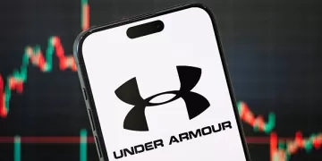 CHONGQING, CHINA - MAY 11: In this photo illustration, the logo of Under Armour, Inc. is displayed on a smartphone screen, with the company's latest stock market chart in the background, reflecting investor sentiment and recent trading activity, on May 11, 2025, in Chongqing, China. Under Armour is an American sportswear and athletic performance apparel company known for its innovative moisture-wicking fabrics and high-performance gear. (Photo illustration by Cheng Xin/Getty Images)