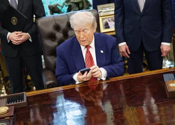 US President Donald Trump holds an Apple Inc. iPhone during an executive order signing in the Oval Office of the White House in Washington, DC, US, on Friday, May 23, 2025. Trump on Friday signed orders meant to accelerate the construction of nuclear power plants, including small, untested designs that offer the promise of rapid deployment but have yet to be built in the US. Photographer: Samuel Corum/Sipa/Bloomberg via Getty Images