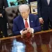 US President Donald Trump holds an Apple Inc. iPhone during an executive order signing in the Oval Office of the White House in Washington, DC, US, on Friday, May 23, 2025. Trump on Friday signed orders meant to accelerate the construction of nuclear power plants, including small, untested designs that offer the promise of rapid deployment but have yet to be built in the US. Photographer: Samuel Corum/Sipa/Bloomberg via Getty Images