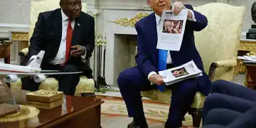 WASHINGTON, DC - MAY 21: U.S. President Donald Trump holds up a printed article from "American Thinker" while accusing South Africa President Cyril Ramaphosa of state-sanctioned violence against white farmers in South Africa during a press availability in the Oval Office at the White House on May 21, 2025 in Washington, DC. Relations between the two countries have been strained since Trump signed an executive order in February that claimed white South Africans are the victims of government land confiscation and race-based “genocide,” while admitting some of those Afrikaners as refugees to the United States. Trump also halted all foreign aid to South Africa and expelled the country’s Ambassador to the U.S., Ebrahim Rasool. (Photo by Chip Somodevilla/Getty Images)