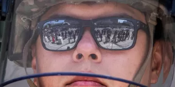Demonstrators are reflected in the glasses of a California National Guard member standing guard outside the Federal Building during a protest in response to federal immigration operations in Los Angeles, on June 9, 2025. US President Donald Trump on June 9 ordered active-duty Marines into Los Angeles, vowing those protesting immigration arrests would be "hit harder" than ever. Protests in Los Angeles, home to a large Latino population, broke out on June 6, triggered by immigration raids that resulted in dozens of arrests of what authorities say are illegal migrants and gang members. (Photo by Apu GOMES / AFP)