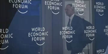 The reflection of an attendee is seen among WEF signage at the National Convention Center in Tianjin on June 24, 2025, on the eve of the opening ceremony for the World Economic Forum Annual Meeting of the New Champions (AMNC25). (Photo by Jade GAO / AFP)
