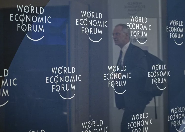 The reflection of an attendee is seen among WEF signage at the National Convention Center in Tianjin on June 24, 2025, on the eve of the opening ceremony for the World Economic Forum Annual Meeting of the New Champions (AMNC25). (Photo by Jade GAO / AFP)