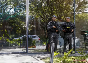 Police officers stand guard outside the REAG Investments building during an operation targeting a money laundering network in Sao Paulo, Brazil, on August 28, 2025. Brazilian police launched a mega operation in several states Thursday to crush a criminal network that sold adulterated fuel to clients and concealed billions of dollars in earnings in cahoots with financial companies. The group allegedly laundered money for the First Capital Command (PCC), one of the country's most powerful gangs engaged in cocaine trafficking from South America to Europe, according to prosecutors. (Photo by Miguel SCHINCARIOL / AFP)