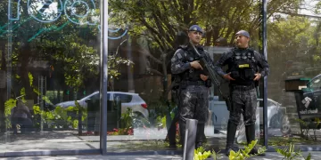 Police officers stand guard outside the REAG Investments building during an operation targeting a money laundering network in Sao Paulo, Brazil, on August 28, 2025. Brazilian police launched a mega operation in several states Thursday to crush a criminal network that sold adulterated fuel to clients and concealed billions of dollars in earnings in cahoots with financial companies. The group allegedly laundered money for the First Capital Command (PCC), one of the country's most powerful gangs engaged in cocaine trafficking from South America to Europe, according to prosecutors. (Photo by Miguel SCHINCARIOL / AFP)