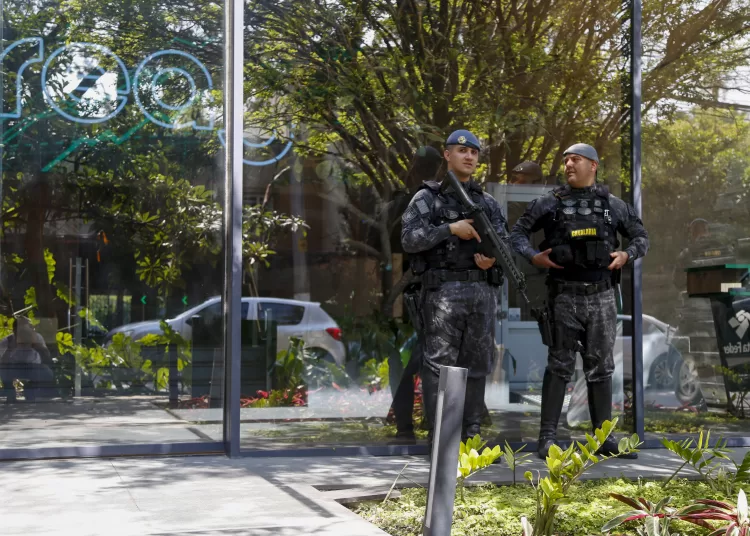 Police officers stand guard outside the REAG Investments building during an operation targeting a money laundering network in Sao Paulo, Brazil, on August 28, 2025. Brazilian police launched a mega operation in several states Thursday to crush a criminal network that sold adulterated fuel to clients and concealed billions of dollars in earnings in cahoots with financial companies. The group allegedly laundered money for the First Capital Command (PCC), one of the country's most powerful gangs engaged in cocaine trafficking from South America to Europe, according to prosecutors. (Photo by Miguel SCHINCARIOL / AFP)