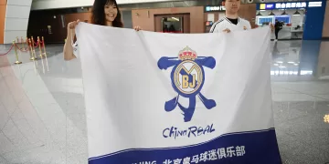 Real Madrid fans from China, Rebecca Feng (L) and Alex Lee pose with a banner at the Beijing Daxing International Airport in Beijing on September 29, 2025, before boarding a flight to Kazakhstan, to watch the football team play in the Champions League. The Spanish giants are playing local minnows Kairat in Kazakhstan's biggest city Almaty on September 30, a game sports magazine The Athletic called "arguably the biggest mismatch in the competition's history". But for Asian Real Madrid fans, it's a rare opportunity to see their idols without having to travel 7,000 kilometres or more to Europe. (Photo by GREG BAKER / AFP)