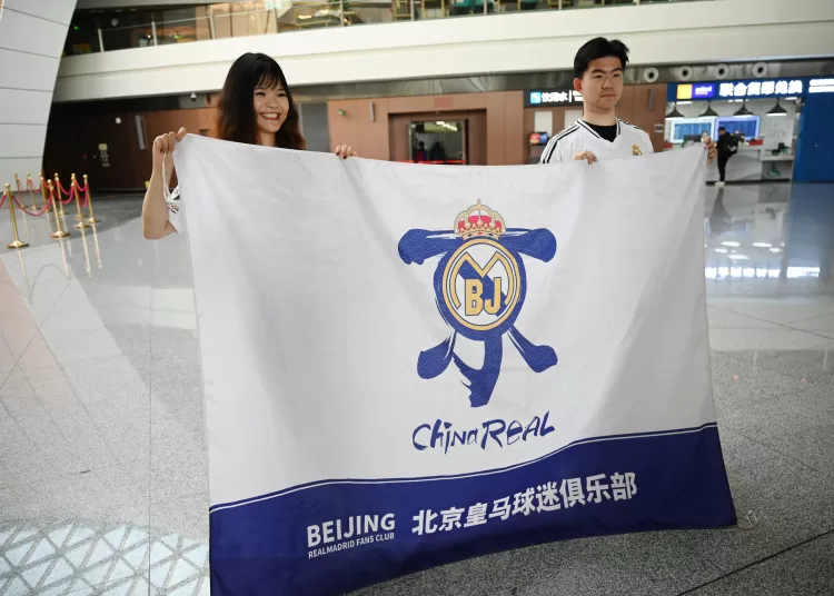 Real Madrid fans from China, Rebecca Feng (L) and Alex Lee pose with a banner at the Beijing Daxing International Airport in Beijing on September 29, 2025, before boarding a flight to Kazakhstan, to watch the football team play in the Champions League. The Spanish giants are playing local minnows Kairat in Kazakhstan's biggest city Almaty on September 30, a game sports magazine The Athletic called "arguably the biggest mismatch in the competition's history". But for Asian Real Madrid fans, it's a rare opportunity to see their idols without having to travel 7,000 kilometres or more to Europe. (Photo by GREG BAKER / AFP)