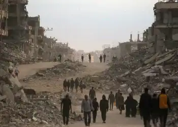 Palestinians make their way past destroyed buildings in Gaza City on October 12, 2025. Hundreds of thousands of Palestinians returned to a devastated Gaza City, after an Israel-Hamas ceasefire came into effect, and as both sides discuss implementing US President Donald Trump's 20-point plan to end the war, which calls for Hamas' disarmament and for the group not to be involved in running post-war Gaza. (Photo by Bashar TALEB / AFP)