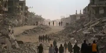 Palestinians make their way past destroyed buildings in Gaza City on October 12, 2025. Hundreds of thousands of Palestinians returned to a devastated Gaza City, after an Israel-Hamas ceasefire came into effect, and as both sides discuss implementing US President Donald Trump's 20-point plan to end the war, which calls for Hamas' disarmament and for the group not to be involved in running post-war Gaza. (Photo by Bashar TALEB / AFP)
