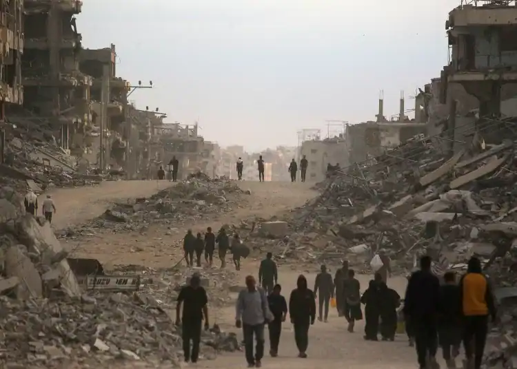 Palestinians make their way past destroyed buildings in Gaza City on October 12, 2025. Hundreds of thousands of Palestinians returned to a devastated Gaza City, after an Israel-Hamas ceasefire came into effect, and as both sides discuss implementing US President Donald Trump's 20-point plan to end the war, which calls for Hamas' disarmament and for the group not to be involved in running post-war Gaza. (Photo by Bashar TALEB / AFP)