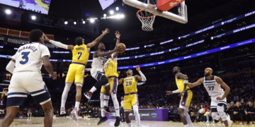 LOS ANGELES, CALIFORNIA - OCTOBER 24: Anthony Edwards #5 of the Minnesota Timberwolves takes a shot against Gabe Vincent #7 and Luka Doncic #77 of the Los Angeles Lakers at Crypto.com Arena on October 24, 2025 in Los Angeles, California. NOTE TO USER: User expressly acknowledges and agrees that, by downloading and or using this photograph, User is consenting to the terms and conditions of the Getty Images License Agreement.   Ronald Martinez/Getty Images/AFP (Photo by RONALD MARTINEZ / GETTY IMAGES NORTH AMERICA / Getty Images via AFP)