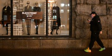 A pdestrian walks past a Mango clothing shop promoting Black Friday sales during a power outage in Kyiv on November 26, 2025, amid the Russian invasion of Ukraine.  (Photo by Sergei GAPON / AFP)