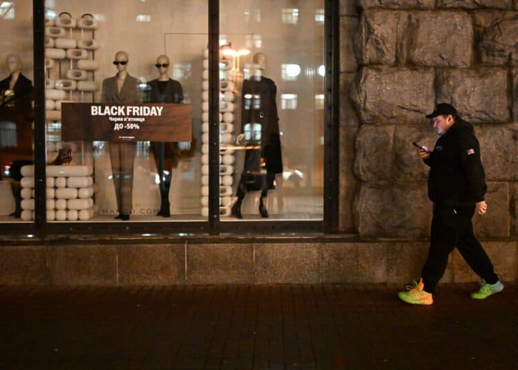 A pdestrian walks past a Mango clothing shop promoting Black Friday sales during a power outage in Kyiv on November 26, 2025, amid the Russian invasion of Ukraine.  (Photo by Sergei GAPON / AFP)