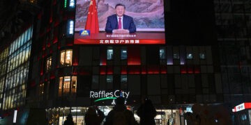 La gente está de pie bajo una gran pantalla que muestra al presidente de China, Xi Jinping, pronunciando un discurso antes de las celebraciones de Nochevieja en Beijing el 31 de diciembre de 2025. El presidente de China, Xi Jinping, dijo el 31 de diciembre que "la reunificación... es imparable" mientras se dirigía a la nación poco después de que el ejército de Beijing anunciara el fin de los simulacros de fuego vivo alrededor de Taiwán. (Foto de WANG Zhao / AFP)
