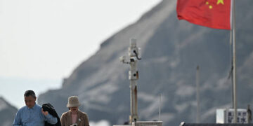 Los visitantes pasan por un poste de cámara de vigilancia (C) y una bandera china (R) en la isla de Pingtan, el punto más cercano a Taiwán, en la provincia de Fujian en el este de China el 30 de diciembre de 2025. Los ejercicios militares de China alrededor de Taiwán entraron en su segundo día el 30 de diciembre, las sextas maniobras importantes que Beijing ha celebrado cerca de la isla autogobernada en los últimos años. (Foto de ADEK BERRY / AFP vía Getty Images)