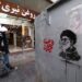 Un iraní pasa junto a una tienda y una imagen del líder supremo asesinado de Irán, el ayatolá Ali Khamenei (R), a lo largo de una calle en la plaza Tajrish en Teherán el 7 de marzo de 2026. El ejército de Irán dijo el sábado que su marina había lanzado una ola de ataques con drones dirigidos a Israel, así como a bases estadounidenses en los Emiratos Árabes Unidos y Kuwait, mientras la guerra regional hacía estragos en su segunda semana. (Foto de ATTA KENARE / AFP)