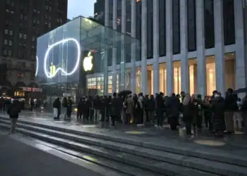Logotipo de Apple sobre una pantalla con datos bursátiles al alza en Wall Street