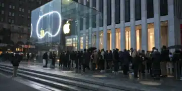 Logotipo de Apple sobre una pantalla con datos bursátiles al alza en Wall Street