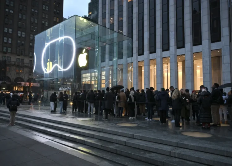 Logotipo de Apple sobre una pantalla con datos bursátiles al alza en Wall Street