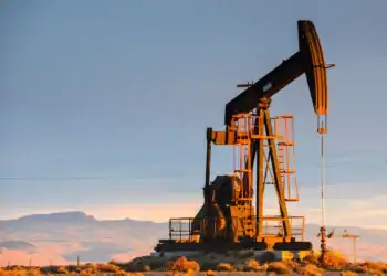 Barriles de petróleo con gráficos financieros a la baja reflejando la caída de los mercados globales
