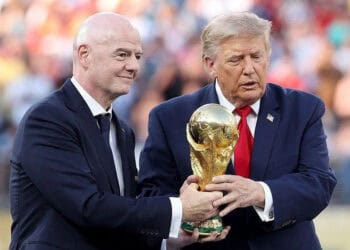 Balón de fútbol frente al logo de la FIFA en una asamblea con banderas de países miembro