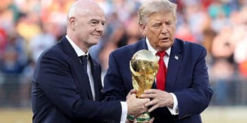 Balón de fútbol frente al logo de la FIFA en una asamblea con banderas de países miembro