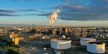 Refinería de petróleo en la costa con tanques de almacenamiento y torres de procesamiento de combustible