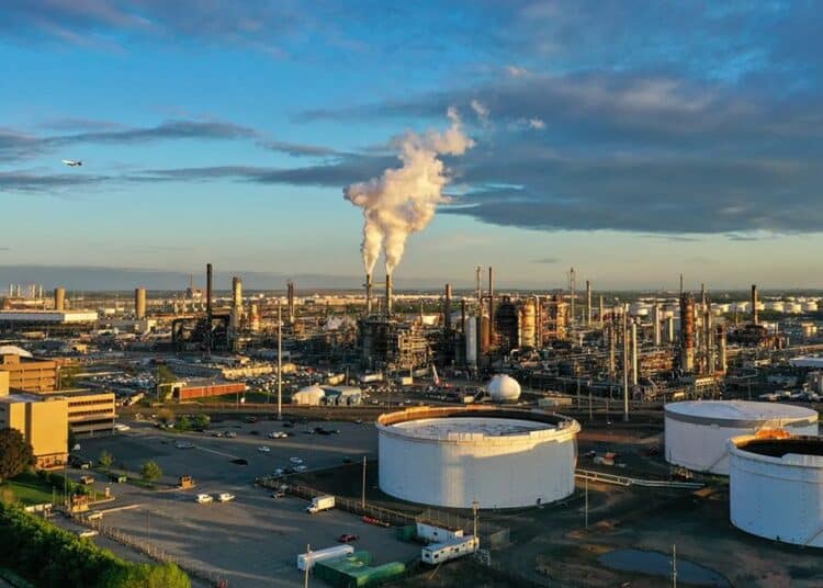 Refinería de petróleo en la costa con tanques de almacenamiento y torres de procesamiento de combustible