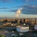 Refinería de petróleo en la costa con tanques de almacenamiento y torres de procesamiento de combustible