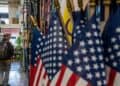 Surtidor de gasolina con precios en descenso frente a un panel de indicadores económicos de Estados Unidos