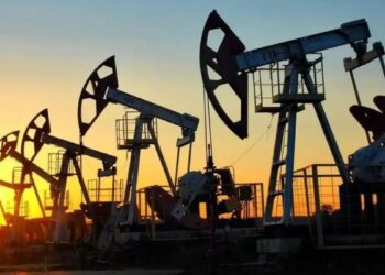 Barriles de petróleo y una plataforma de extracción de crudo con gráfico de precios al fondo