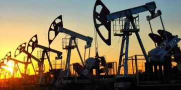 Barriles de petróleo y una plataforma de extracción de crudo con gráfico de precios al fondo