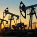 Barriles de petróleo y una plataforma de extracción de crudo con gráfico de precios al fondo