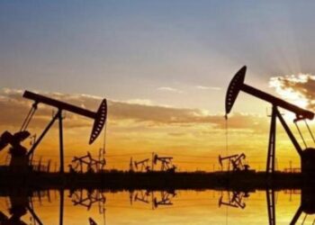 Instalación petrolera con tanques de almacenamiento y precios del crudo a la baja