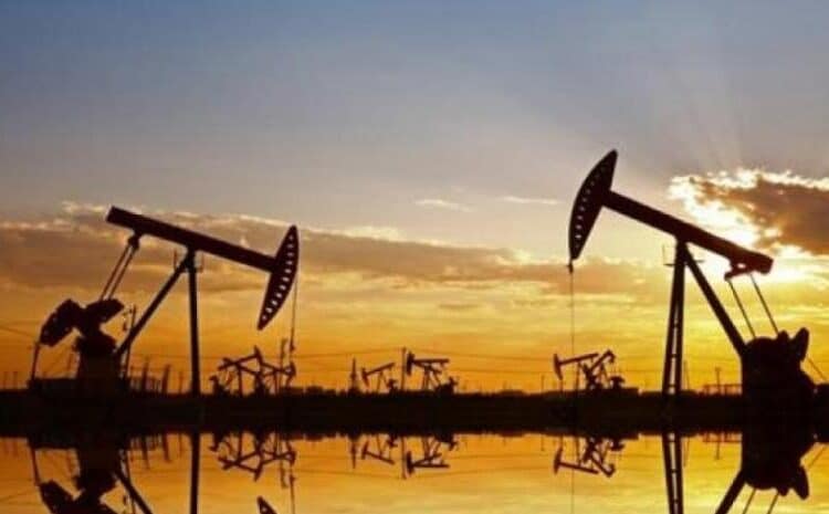 Instalación petrolera con tanques de almacenamiento y precios del crudo a la baja