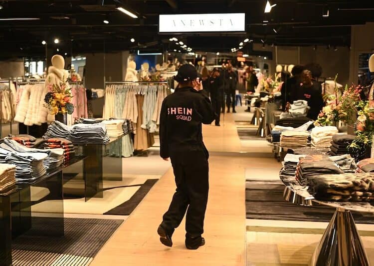 Logotipo de Shein en pantalla junto a paquetes de moda rápida antes de su salida a bolsa