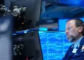 Pantallas de la Bolsa de Nueva York con índices en alza mientras cae el precio del petróleo
