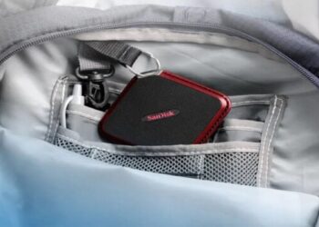 Pantalla bursátil mostrando el alza de las acciones de Sandisk en el Nasdaq junto a unidades de memoria SSD